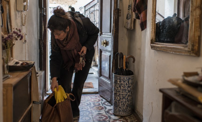 Mujer llegando a trabajar de limpieza por horas a una casa particular y sacando los guantes