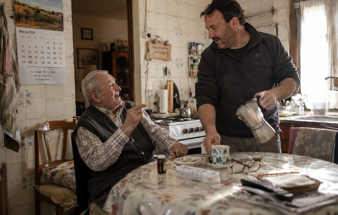 Cuidador sirviendo un caf&eacute; a un se&ntilde;or mayor en la cocina de su casa