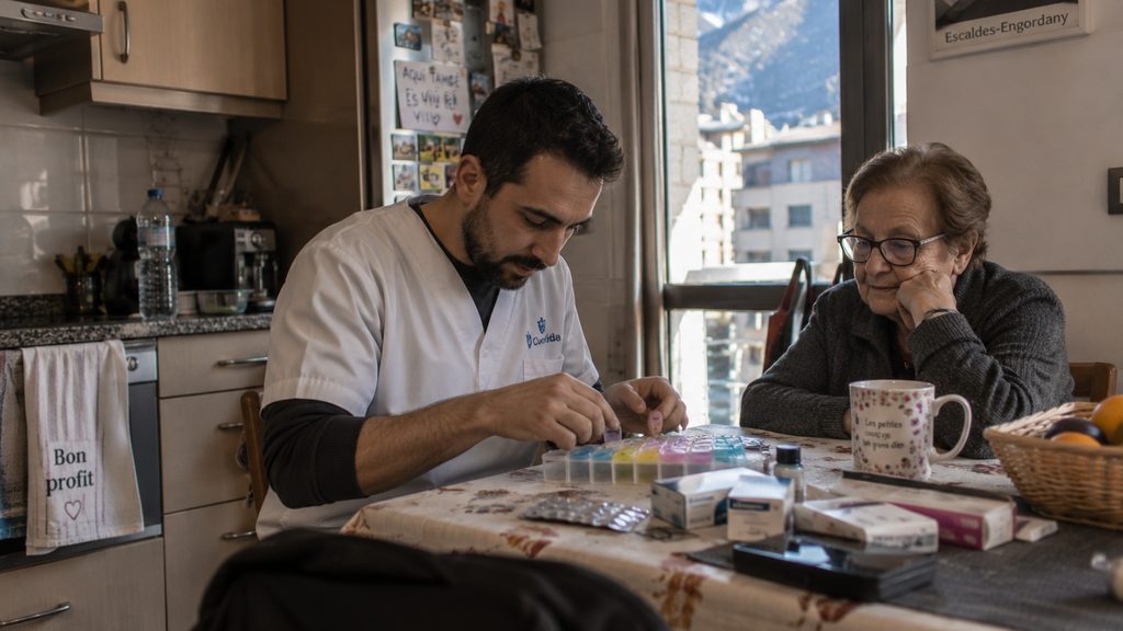 Cuidador preparando el pastillero semanal junto a una señora mayor en un piso de Escaldes-Engordany