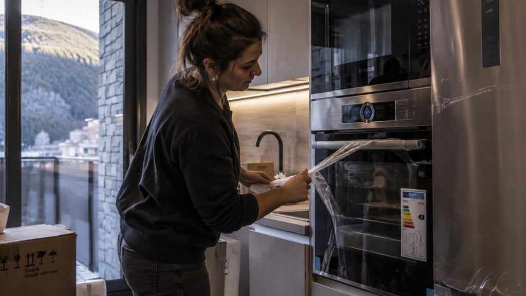 Mujer retirando los plásticos protectores de los electrodomésticos en una cocina recien instalada en Canillo
