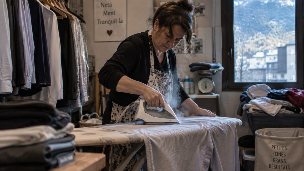 Mujer planchando camisas en el cuarto de plancha de una casa de Andorra