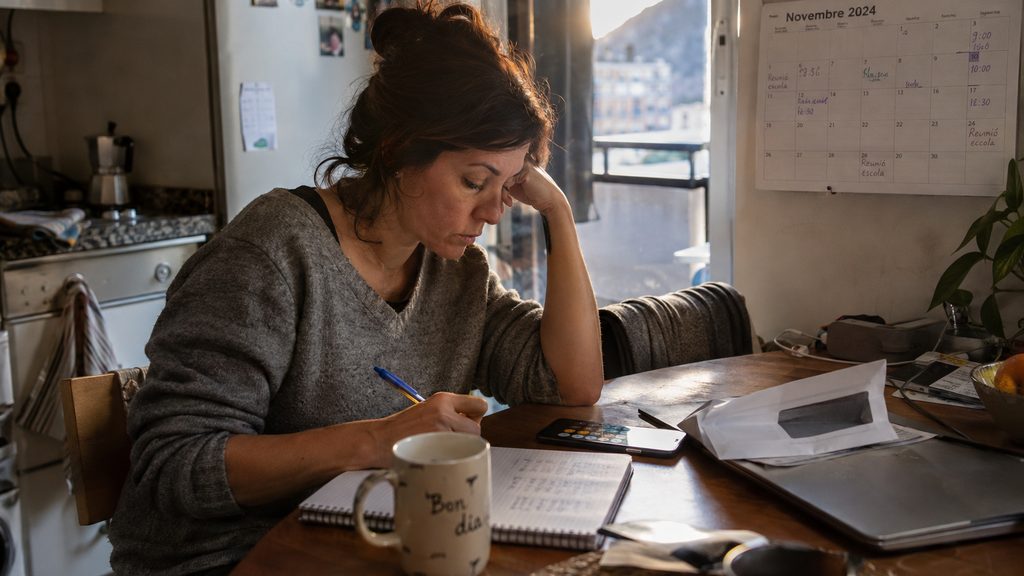 Mujer calculando en una libreta lo que le cuesta al mes la limpieza por horas en su casa de Andorra